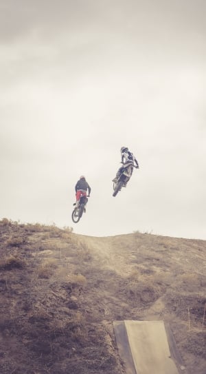 timelapse photography of two motocross drivers on top of a hill thumbnail