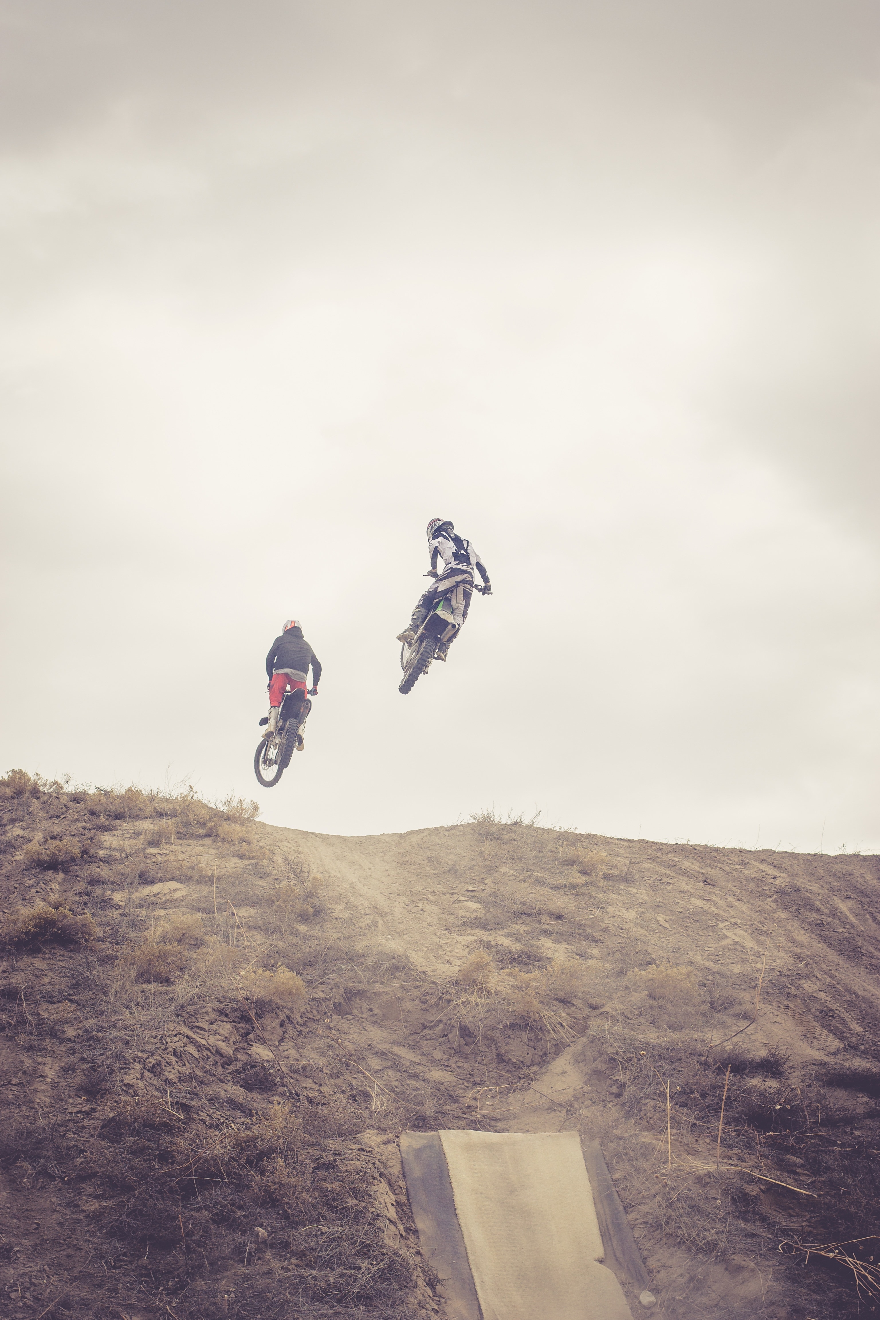 timelapse photography of two motocross drivers on top of a hill