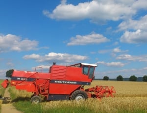 red tractor on rice field during daytime thumbnail