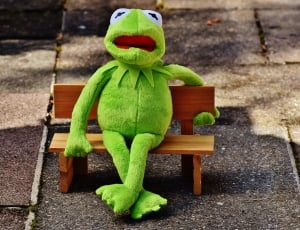 green frog plush toy sitting on miniature bench thumbnail