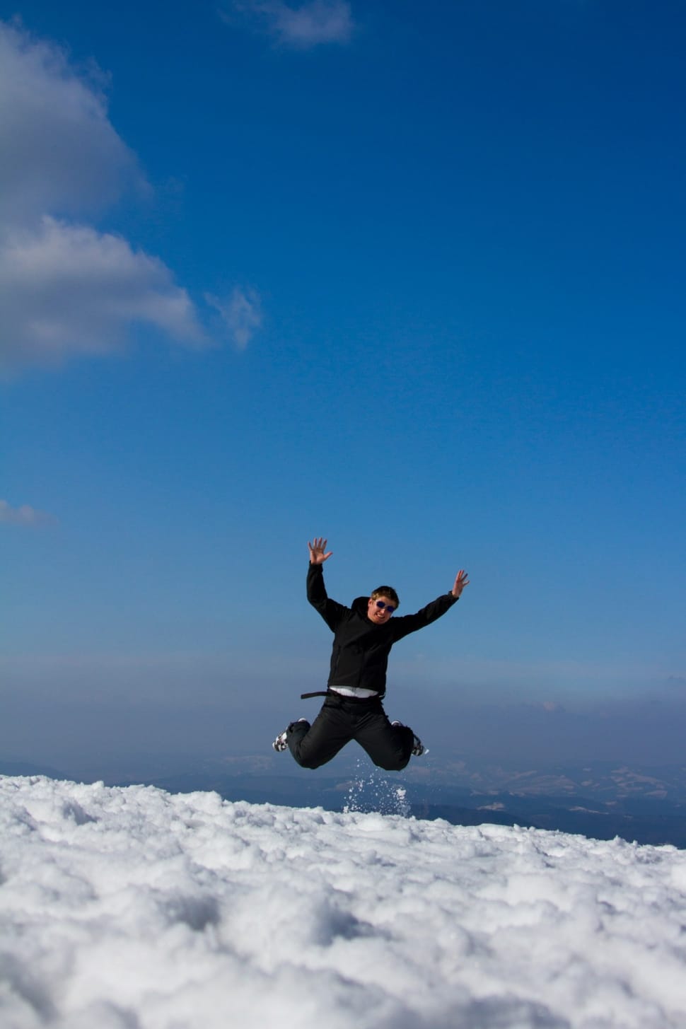man in black pullover hoodie jumping on snow during daytime preview