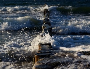 wooden dock on body of water with wave thumbnail