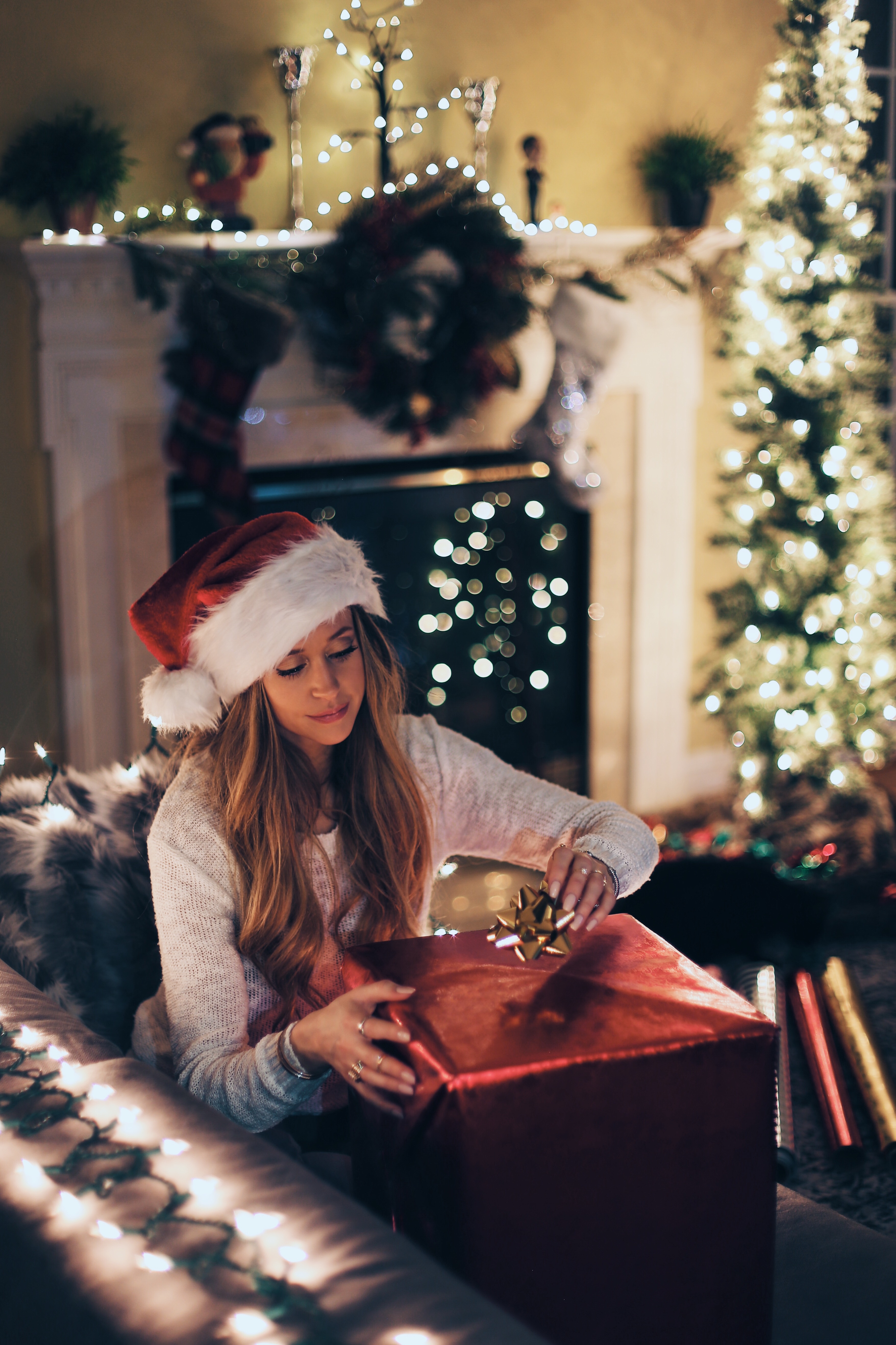 woman in white long sleeve shirt with white and red santa hat sitting on gray sofa