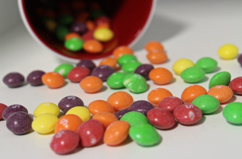 close-up photo of multicolored chocolate coated candies placed on white panel preview