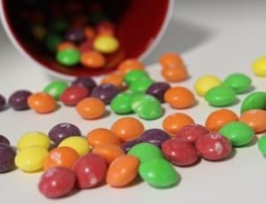 close-up photo of multicolored chocolate coated candies placed on white panel thumbnail