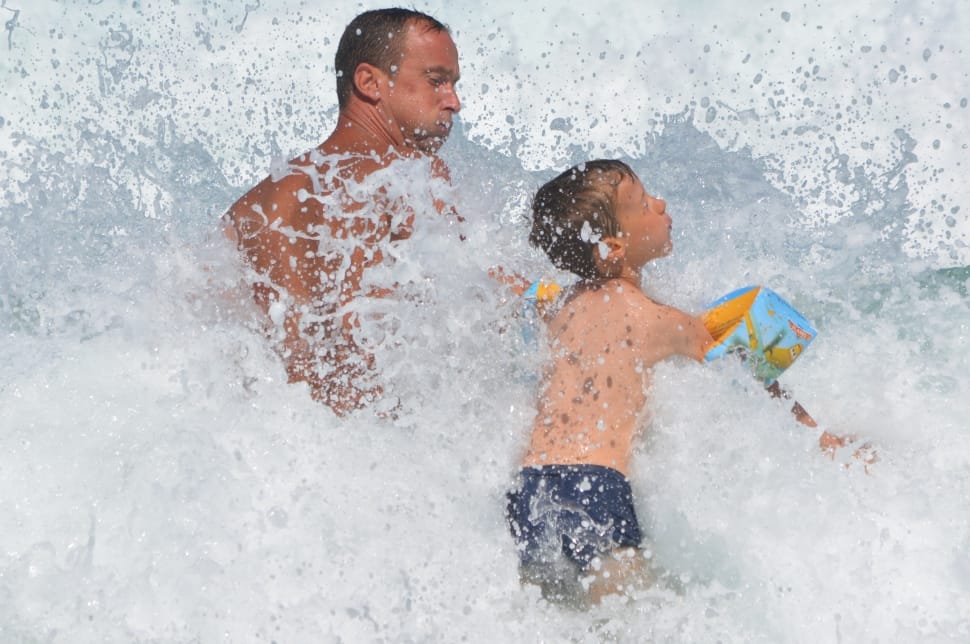 man and boy hit by waves photo preview