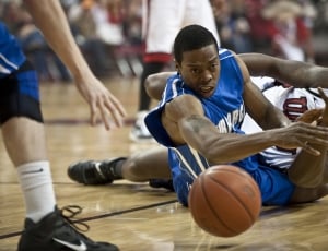 two opposing basketball players diving for the ball thumbnail