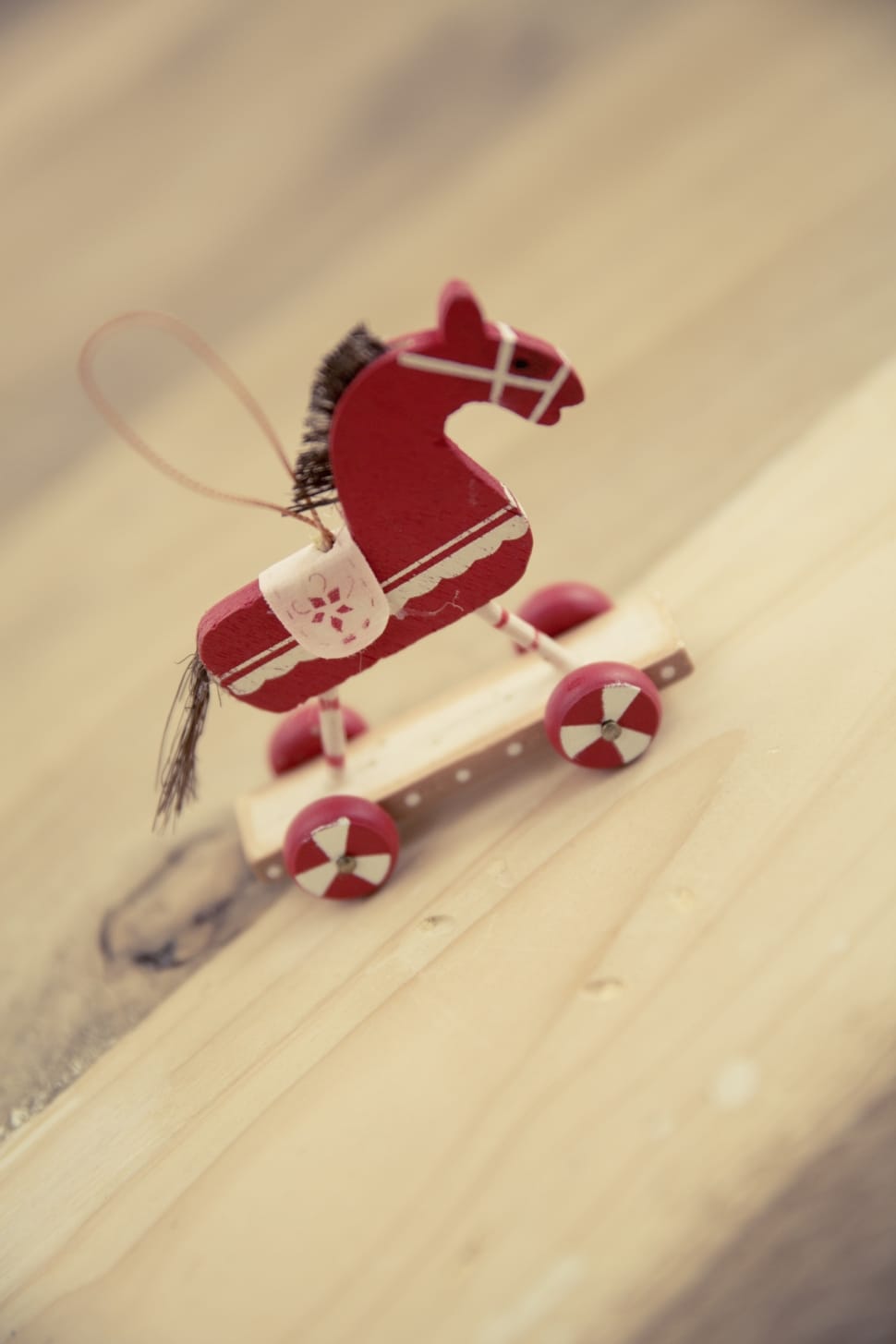 red and white wooden horse toy with wheels macro photography preview