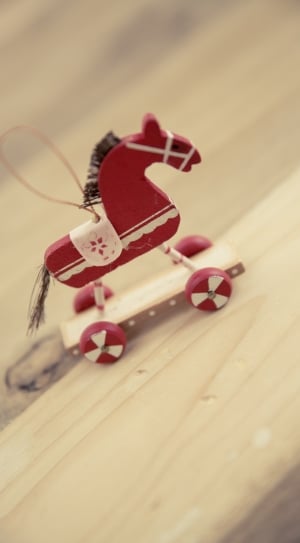 red and white wooden horse toy with wheels macro photography thumbnail