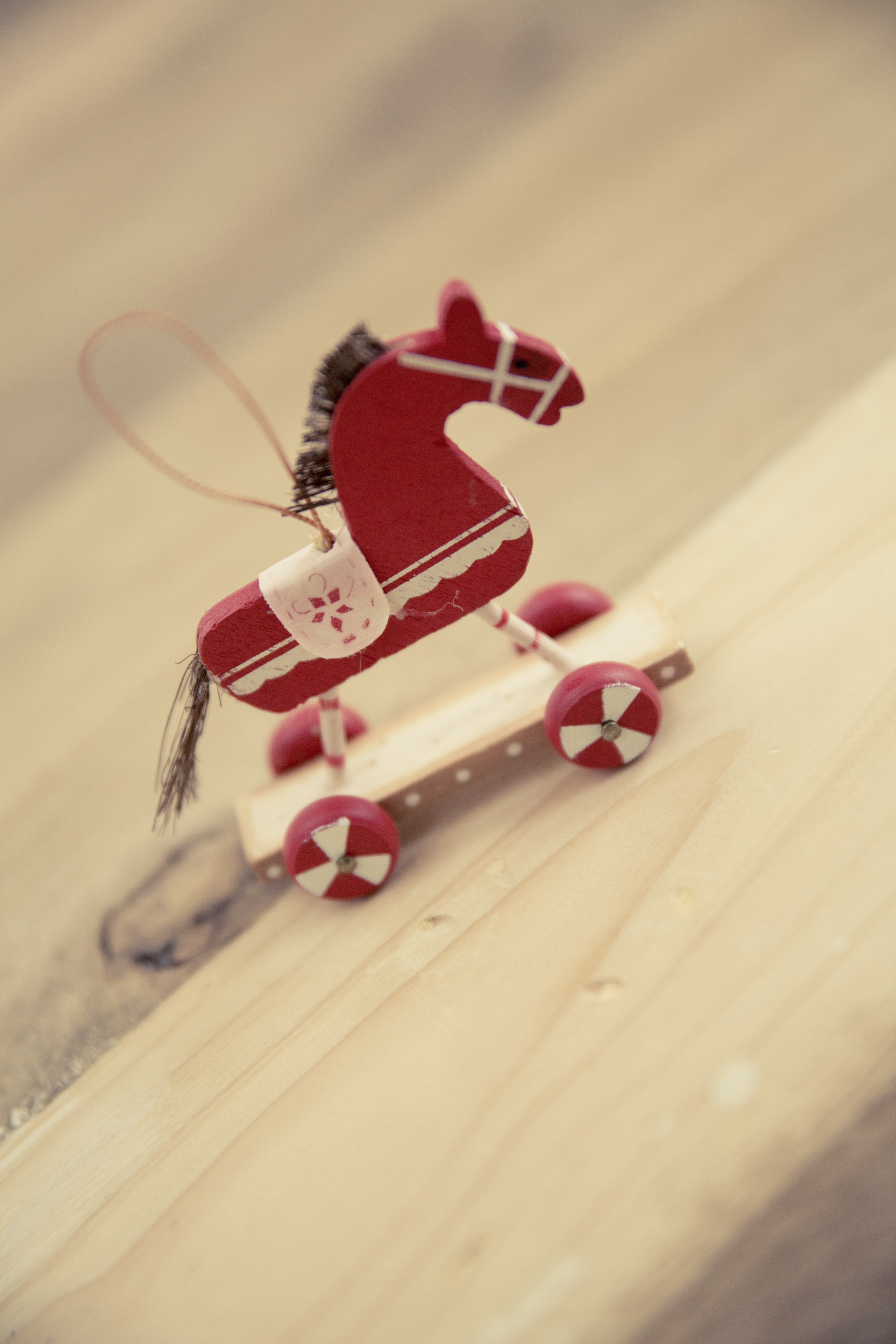 red and white wooden horse toy with wheels macro photography