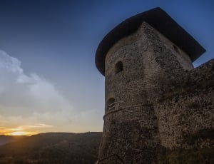 gray brick wall of a tower during sunrise thumbnail