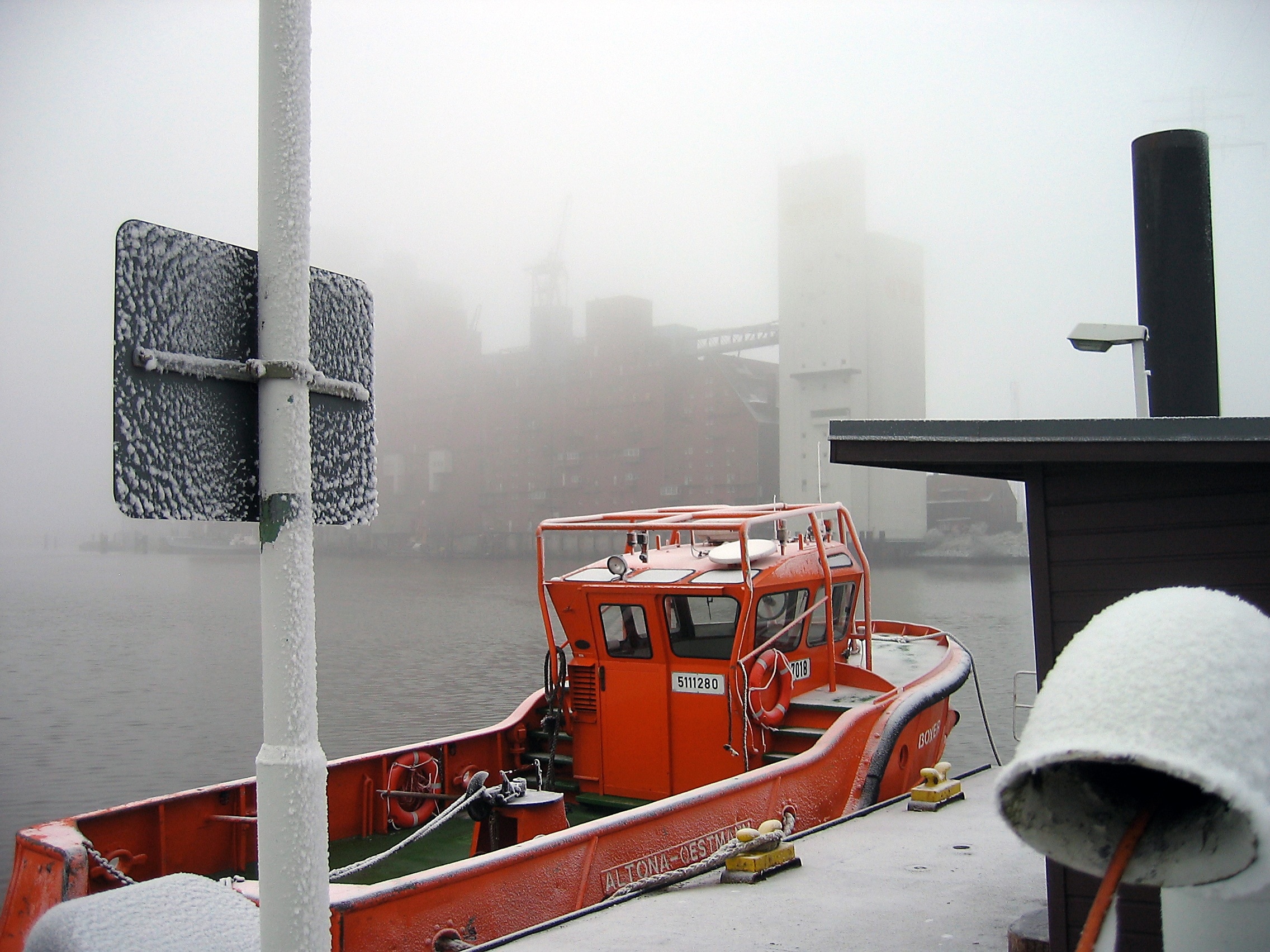 red fishing vessel beside a dock during winter