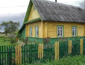 yellow and green wooden house under cloudy sky thumbnail