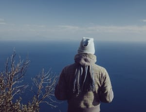 person standing on higher place sight seeing blue ocean under blue sunny sky thumbnail