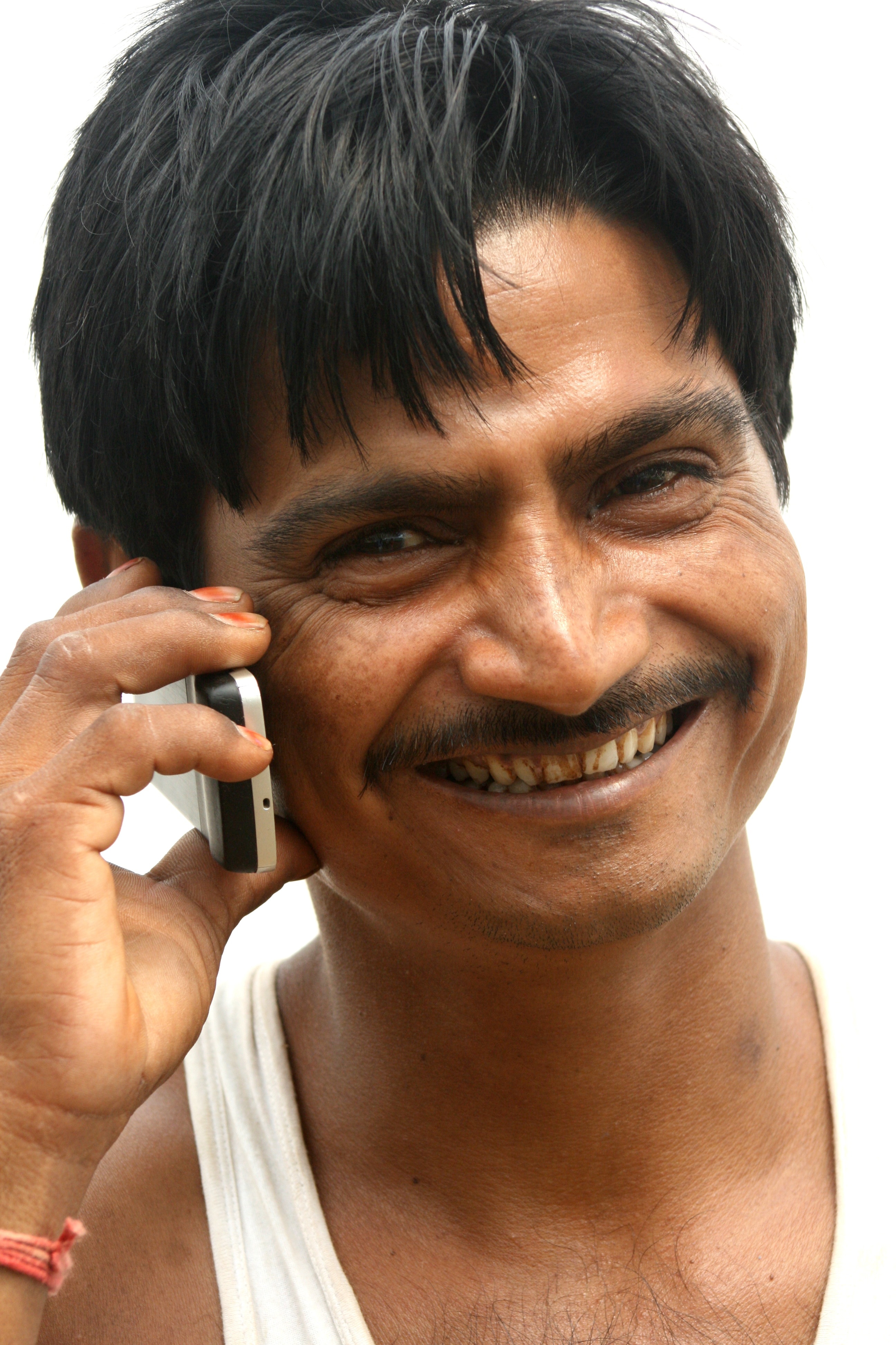 man wearing white tank top holding white and black candybar phone
