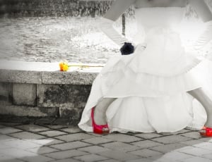 greyscale photo of person in white strapless dress sitting on grey concrete bench thumbnail