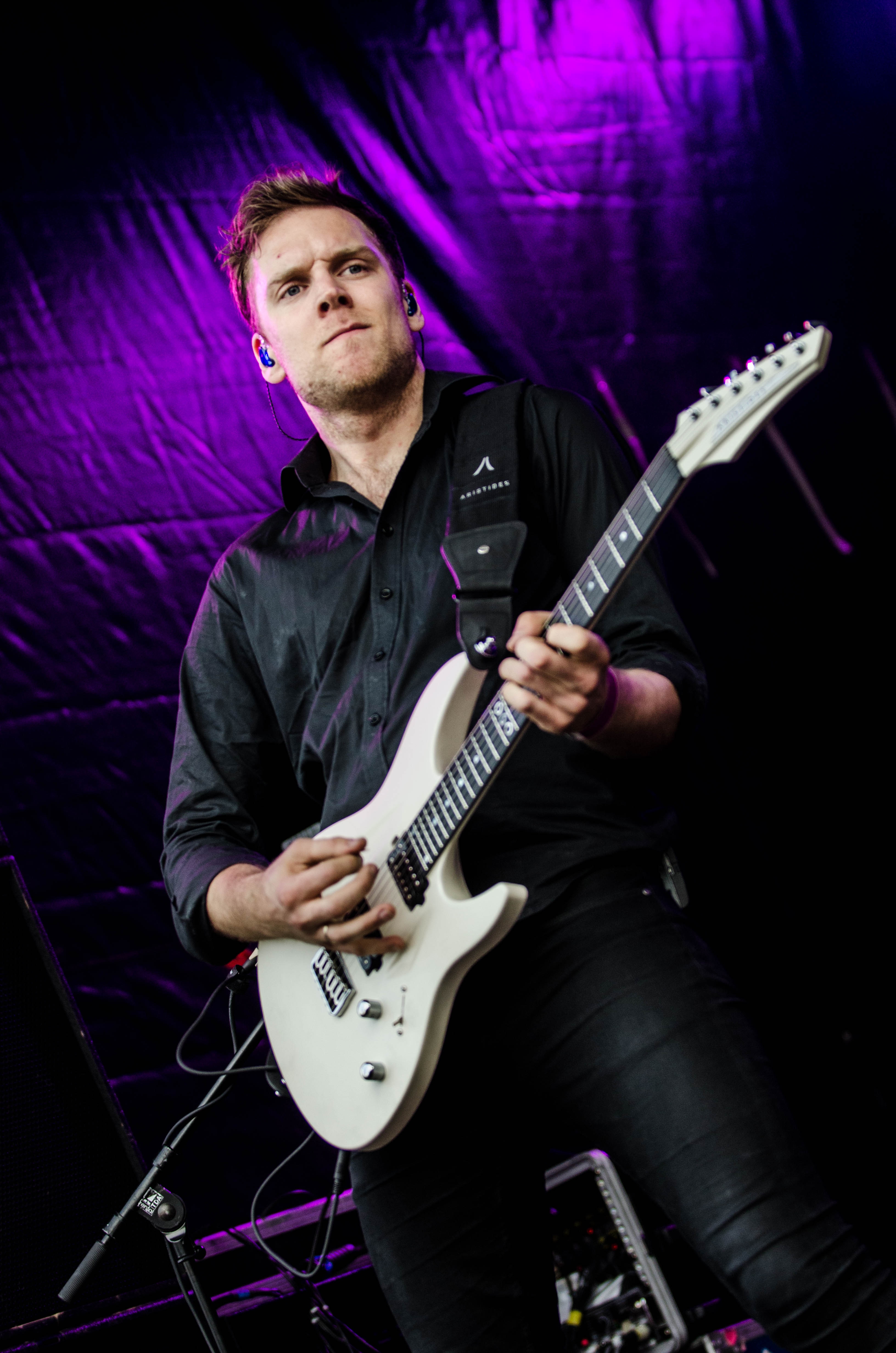 man playing white electric guitar on stage
