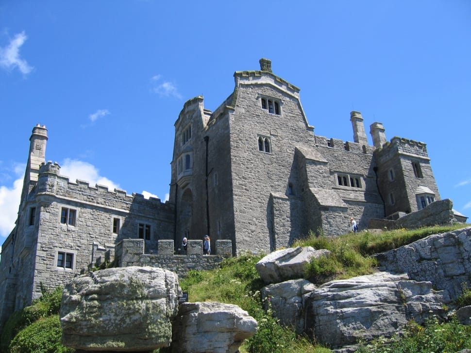 grey concrete building surrounded by grass mountain under blue sky during daytime preview