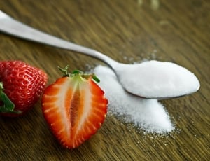 stainless steel spoon with sugar and red sliced strawberry thumbnail