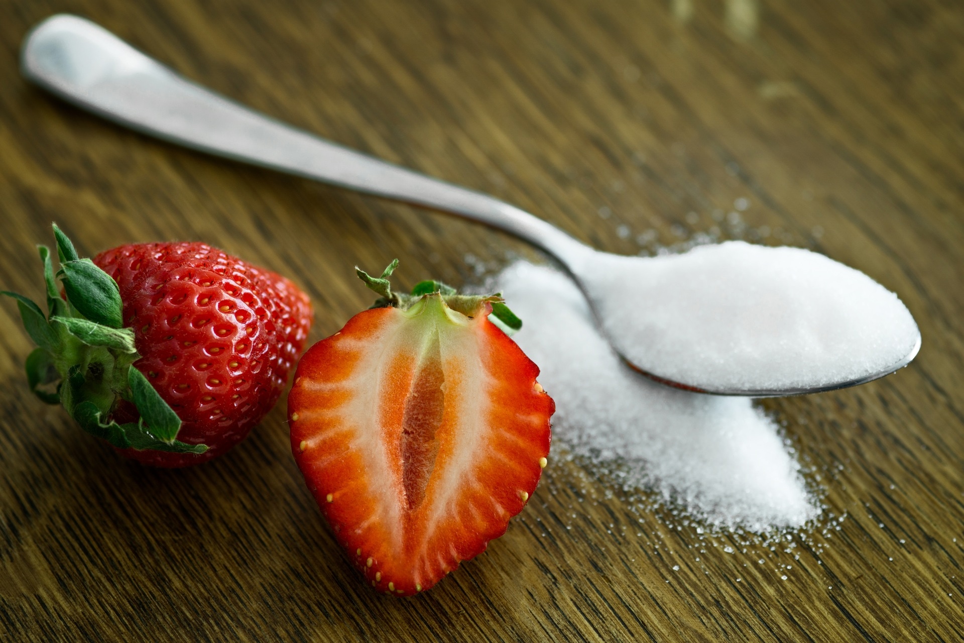 stainless steel spoon with sugar and red sliced strawberry