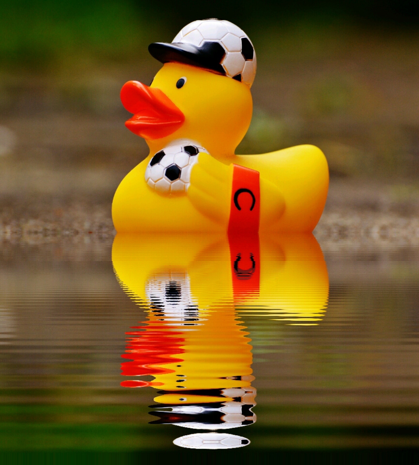 shallow focus photography of soccer player rubber ducky on body of water