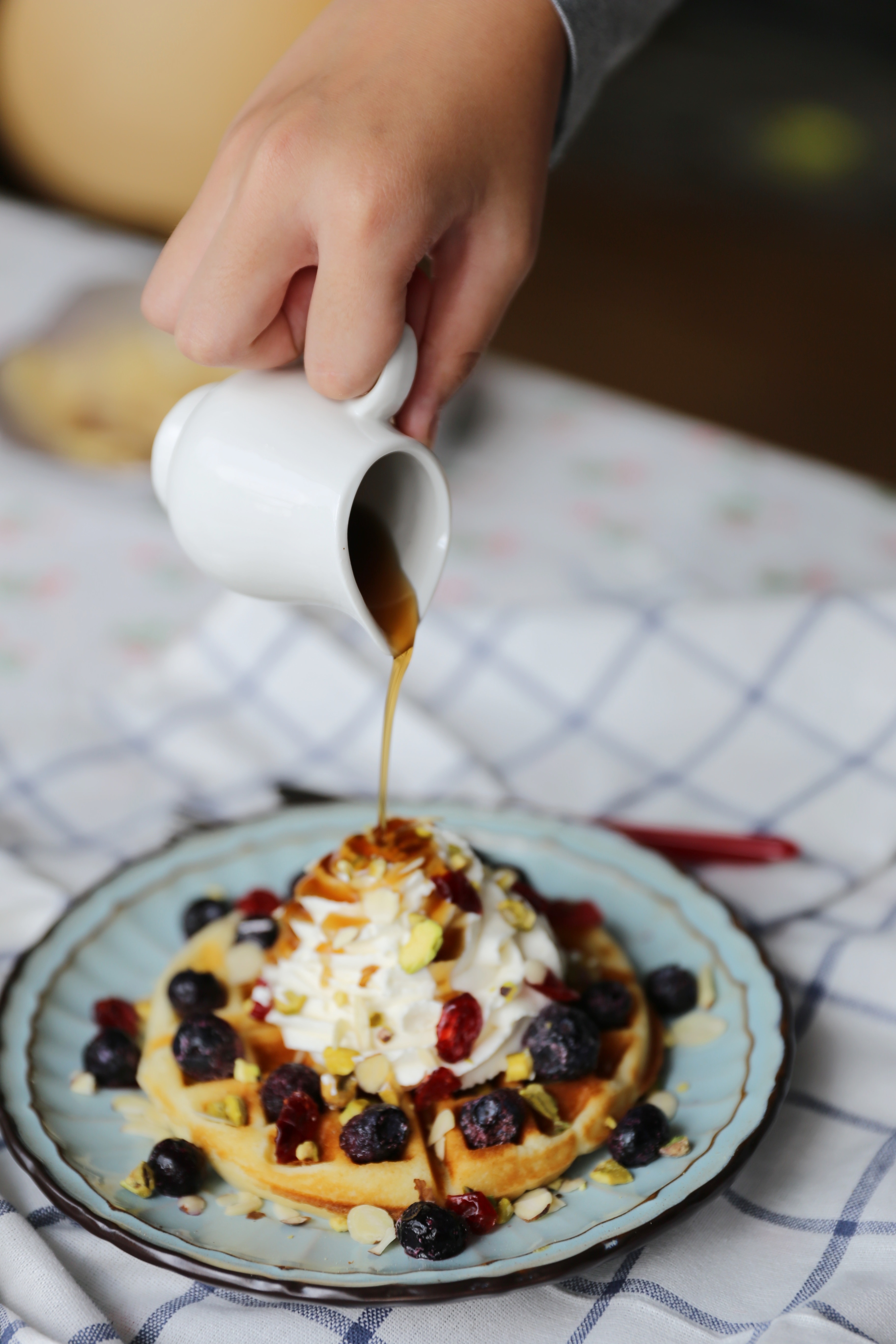 selective focus photo of waffle with whip cream and raisin on ceramic plate
