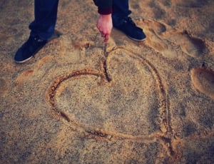 Hand drawing heart in the sand thumbnail