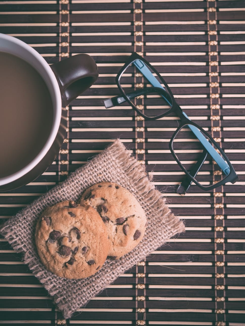 two chocolate chip cookie; brown ceramic mug with coffee; black ...