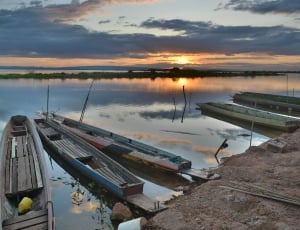 three punt boats on still body of water during sunset thumbnail