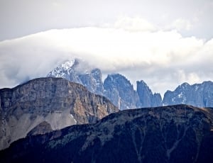 gray mountains filled with snow under the white cloudy sky thumbnail