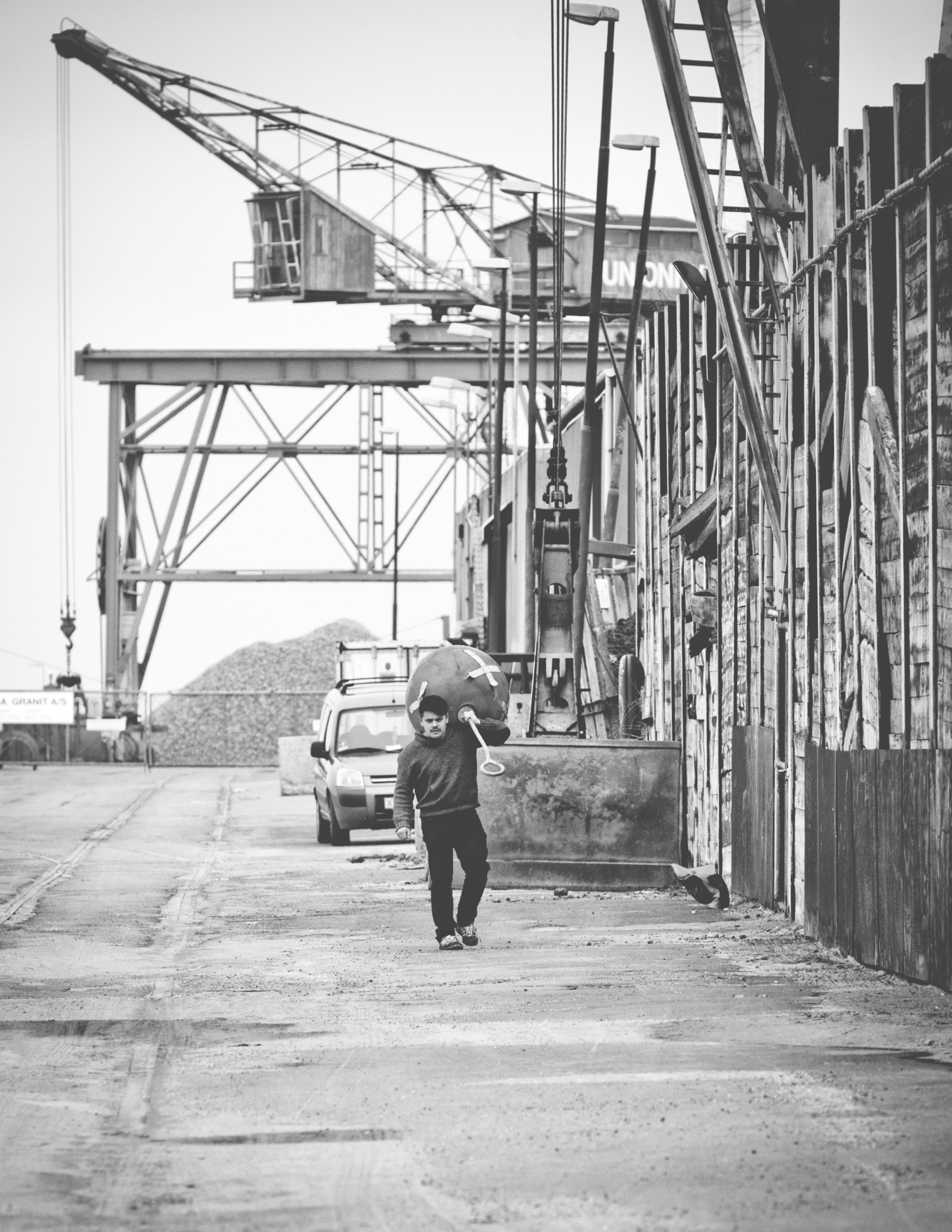 man carrying metal equipment grayscale photo
