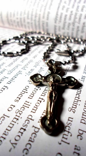 silver crucifix pendant necklace on book thumbnail