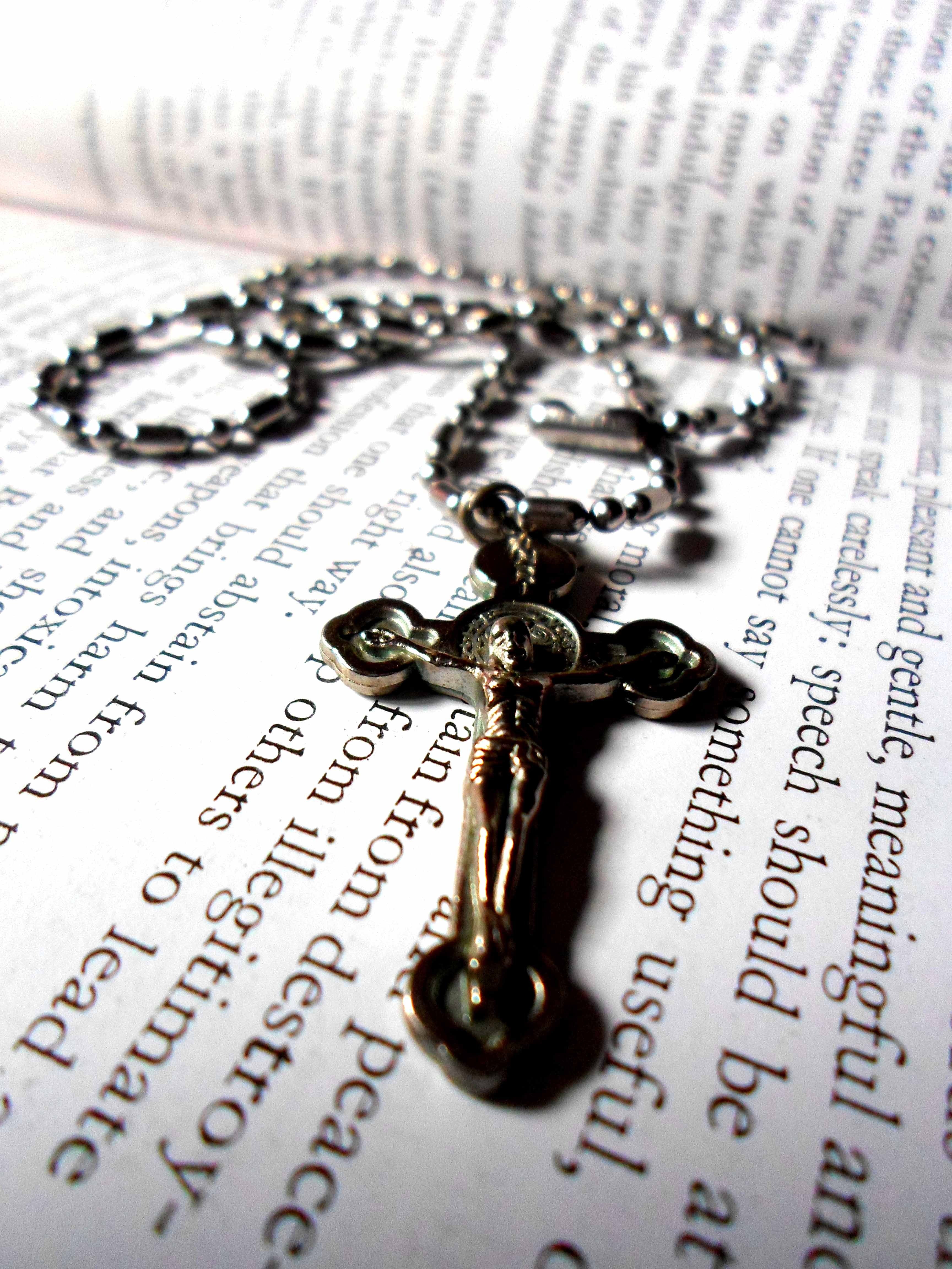 silver crucifix pendant necklace on book