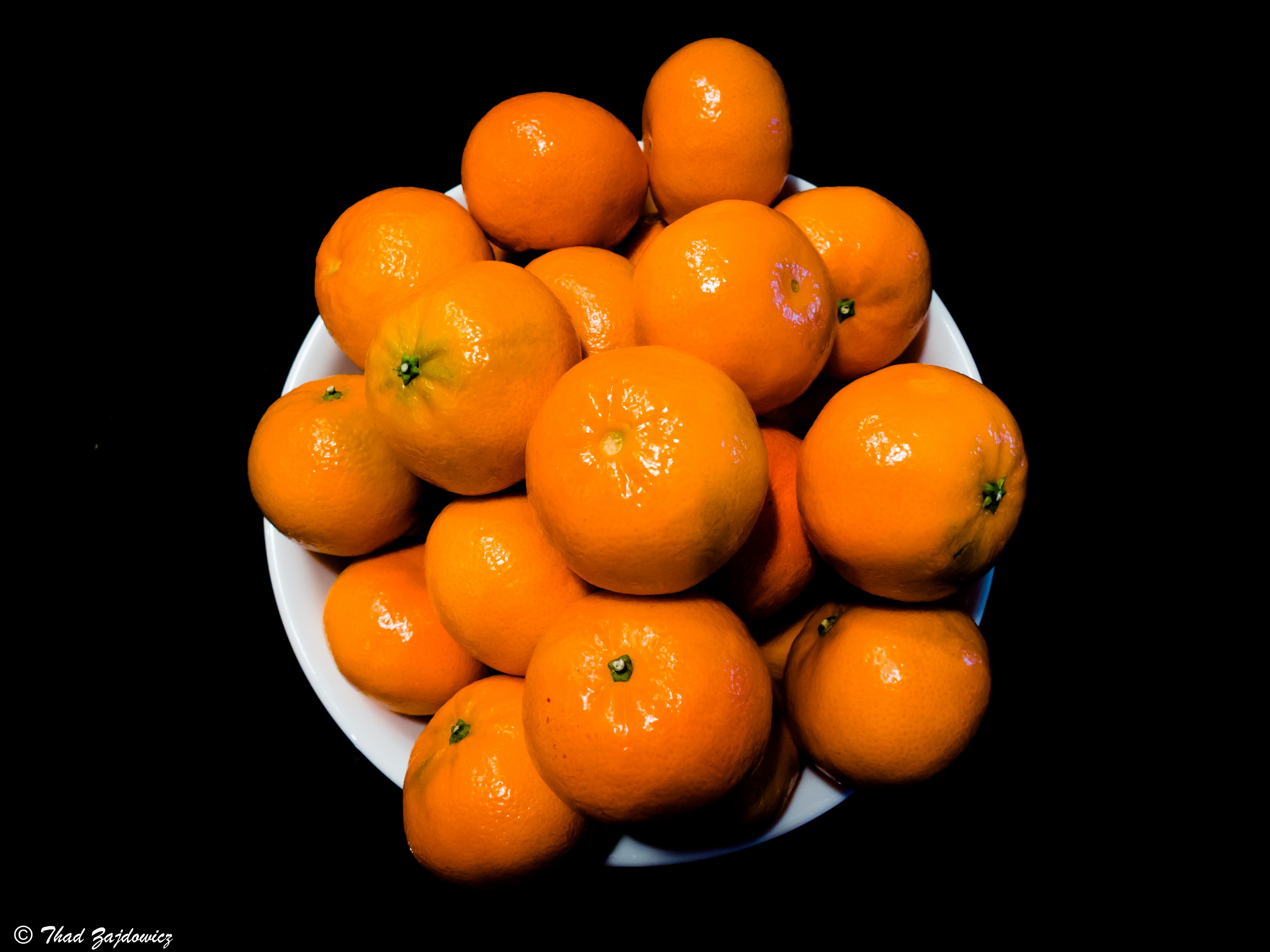 Clementines on disk in black background