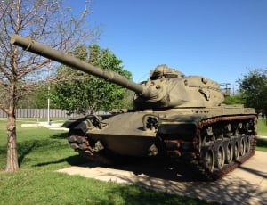 gray steel tank beside brown bare trees under blue sky during daytime thumbnail