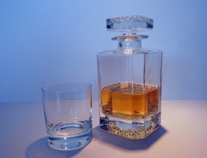 brandy inside clear glass decanter beside clear shot glass thumbnail