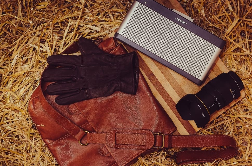 brown leather crossbody bag and black dslr camera lens preview