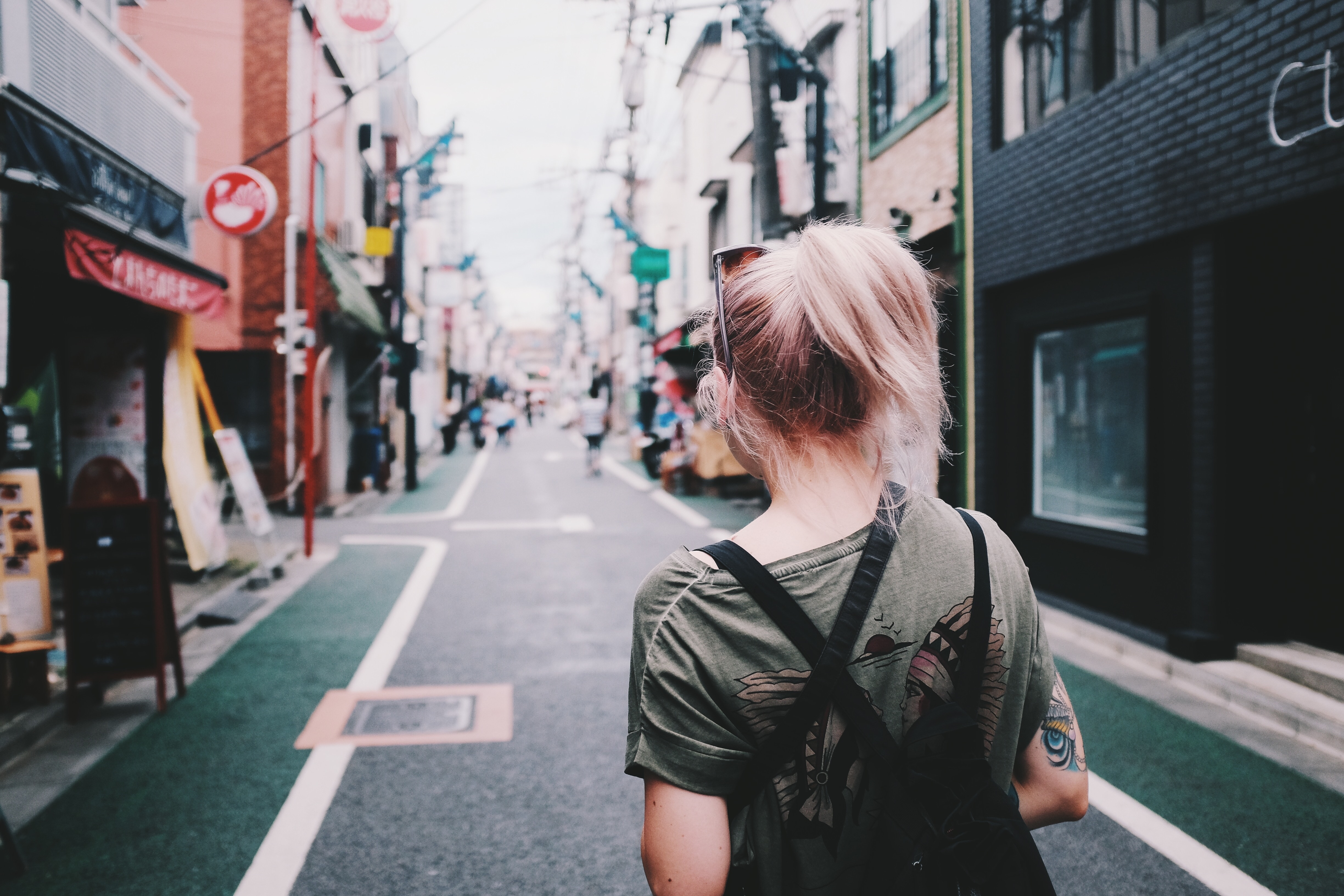 woman with backpack walking on street between buildings