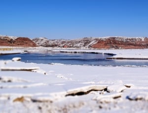 landscape photography of body of water covered with melting snow with mountain as background thumbnail