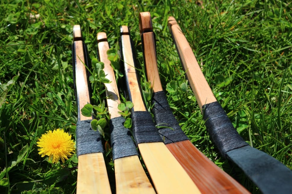 five brown hockey sticks in grass field preview