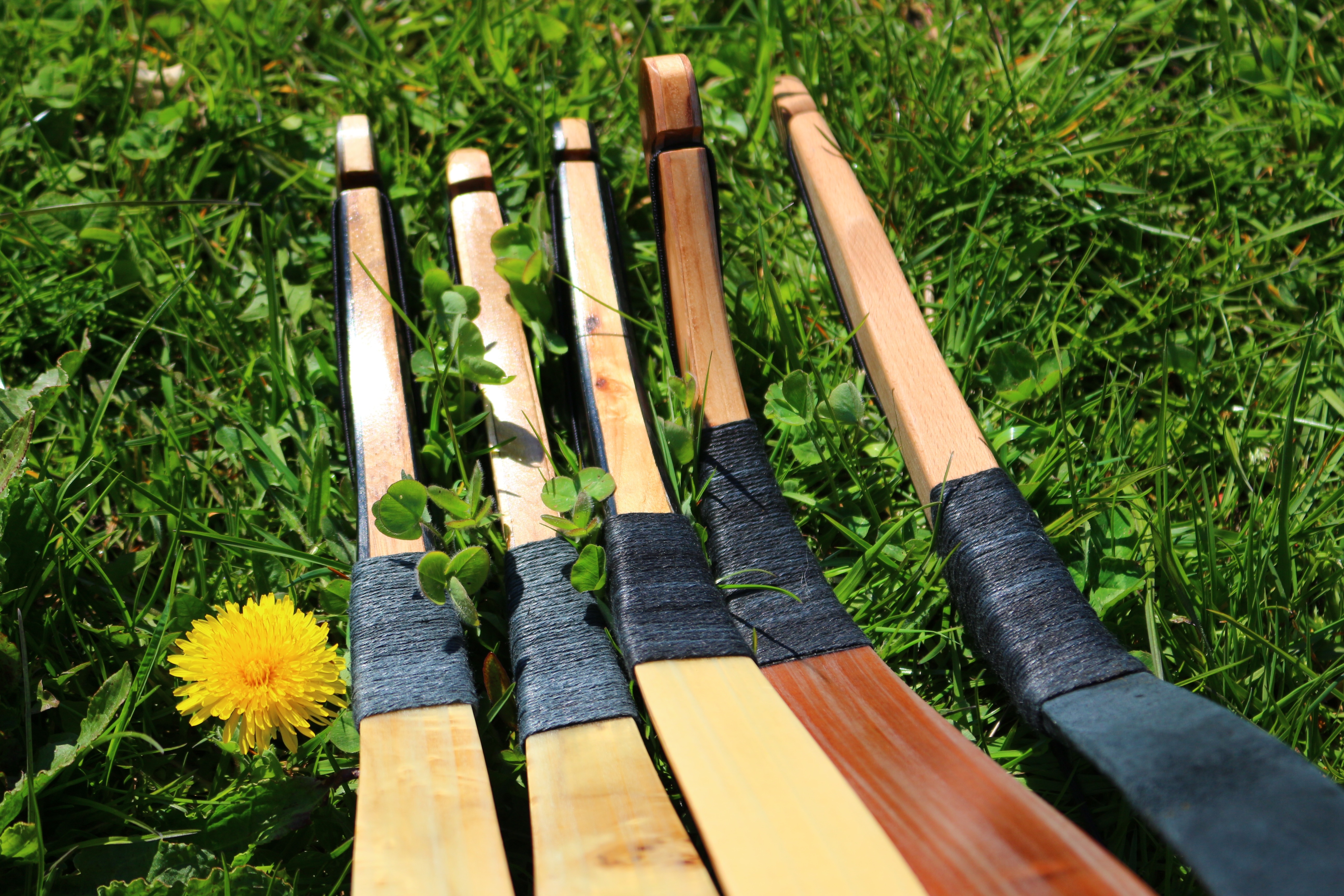 five brown hockey sticks in grass field