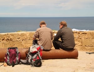 two men sitting on cylindrical part thumbnail
