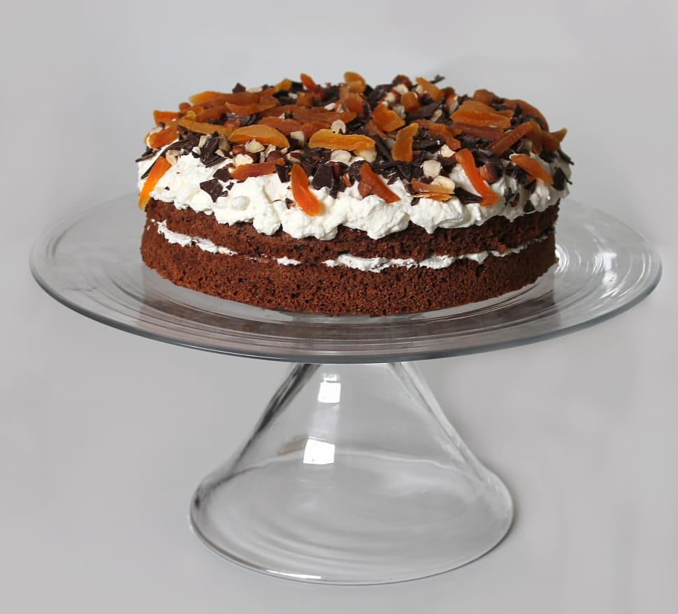 brown cake with icing and chocolates on clear cake dish preview