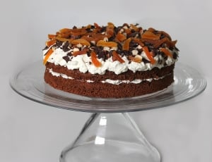 brown cake with icing and chocolates on clear cake dish thumbnail