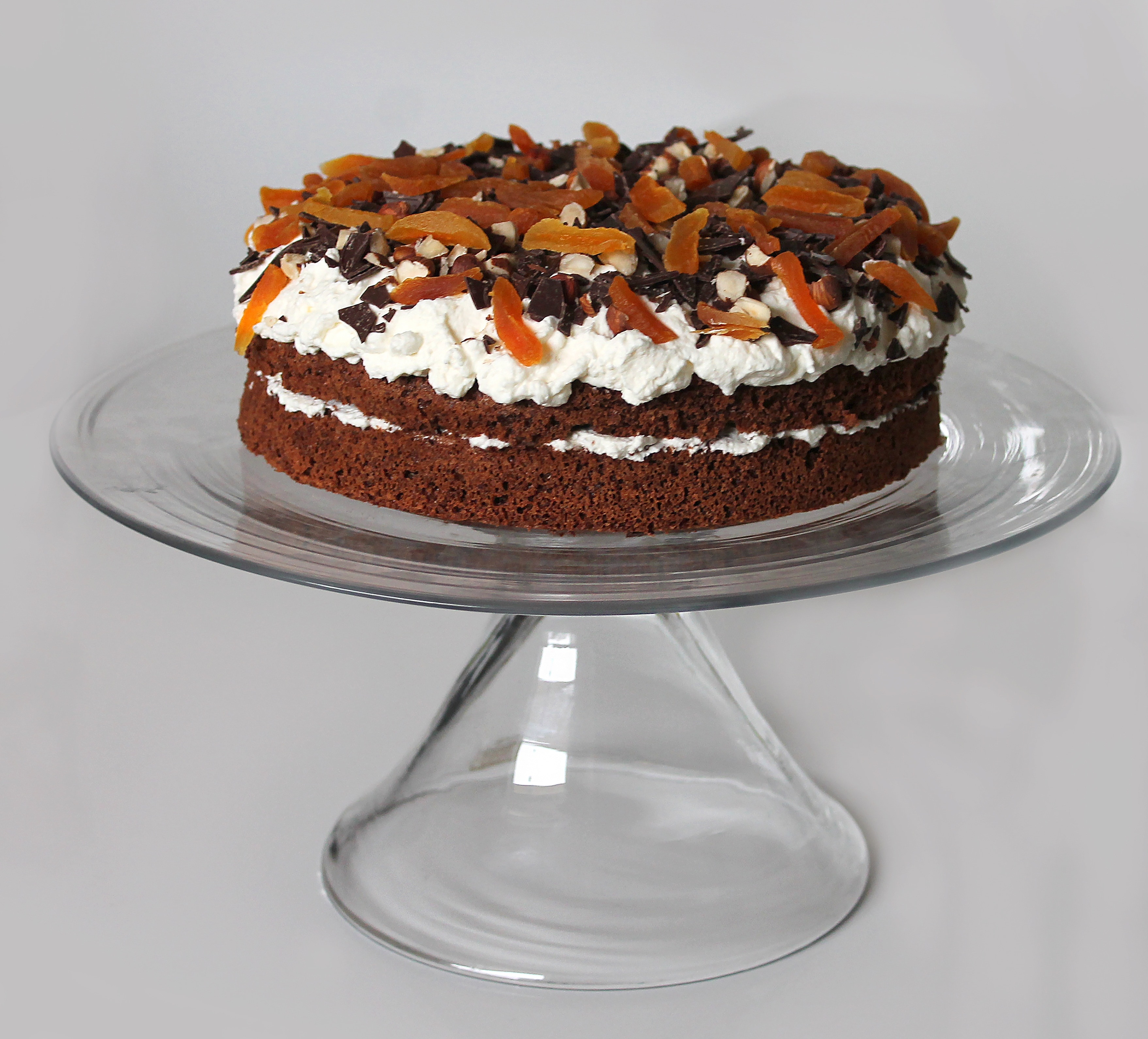 brown cake with icing and chocolates on clear cake dish