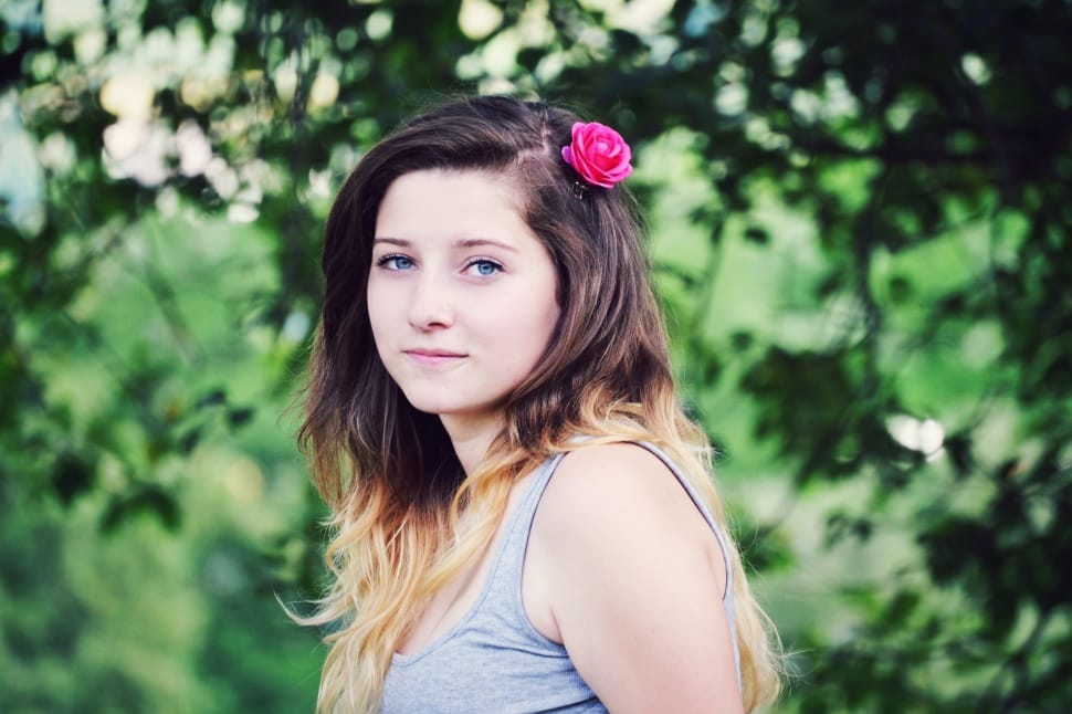selective focus photography of a woman wearing grey tank top with rose in her hair preview