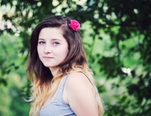 selective focus photography of a woman wearing grey tank top with rose in her hair thumbnail