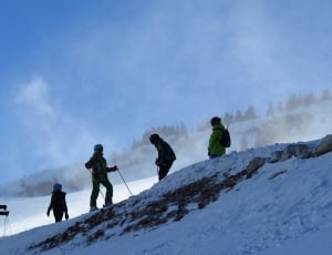 four persons skiing on snow capped mountain during day thumbnail