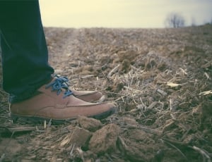 person in jeans and brown shoes standing on brown soil ground\ thumbnail