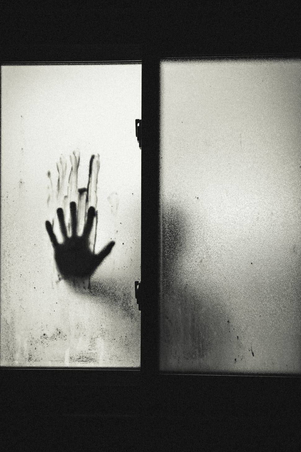 grayscale photo of a person with right stained hand on glass window preview